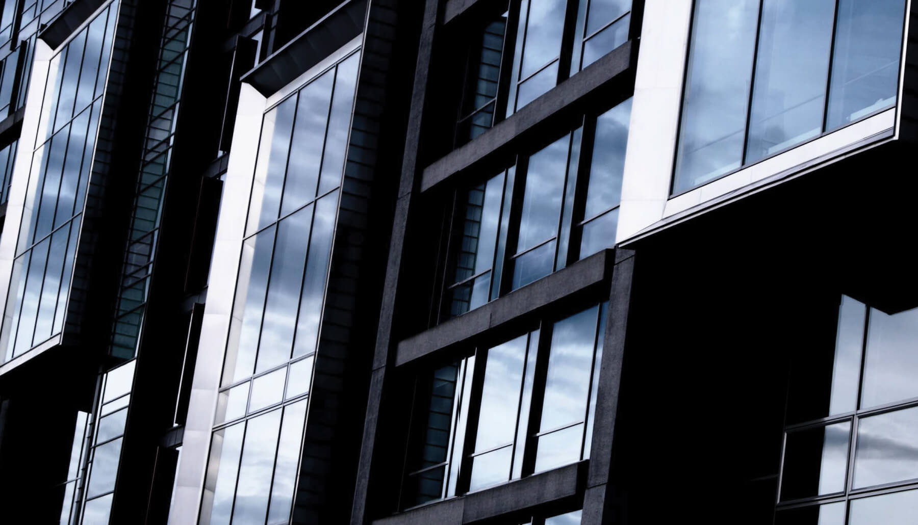 Modernistyczny budynek z oknami Veka odbijającymi niebo.